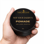 Load image into Gallery viewer, Habd holding a jar of Tabor and Olive Pomade on a white background