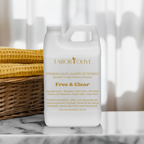 Laundry detergent container sitting on a marble platform next to basket of gold colored linens.