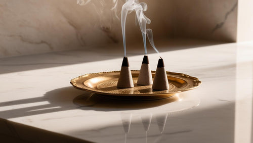 Three incense cones burning on gold plate on marble countertop