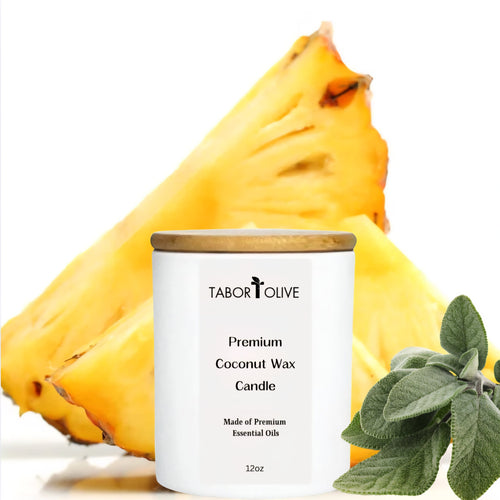 Whote candle with bamboo lid next to cut slices of pineapples and green sage leaves.