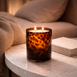 Load image into Gallery viewer, Cheetah Print Candle jar on a table next to a book with a bed in the background setting a calm tone.

