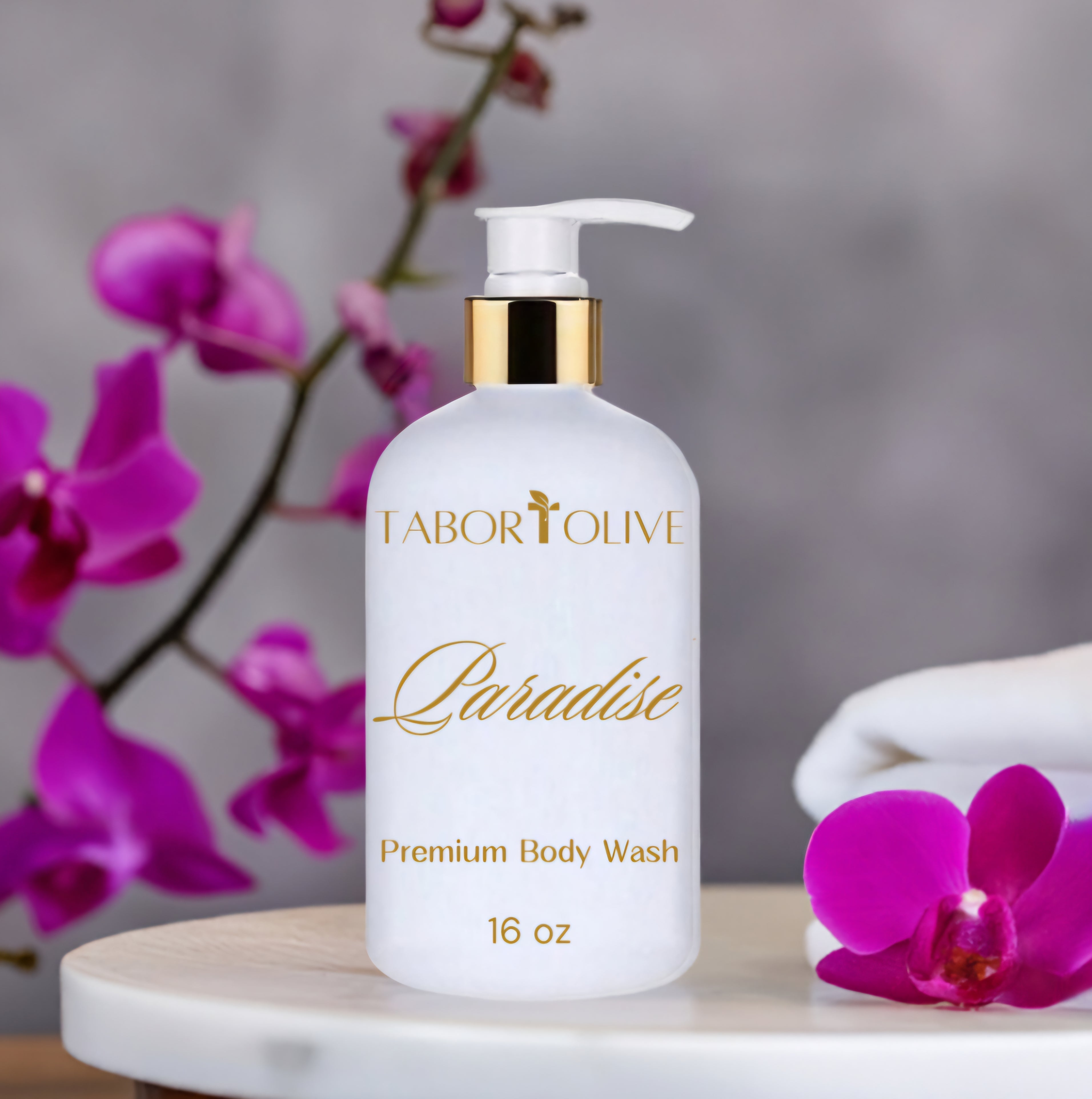 White and gold cosmetic bottle on marble platform next to pink orchid flowering branches.