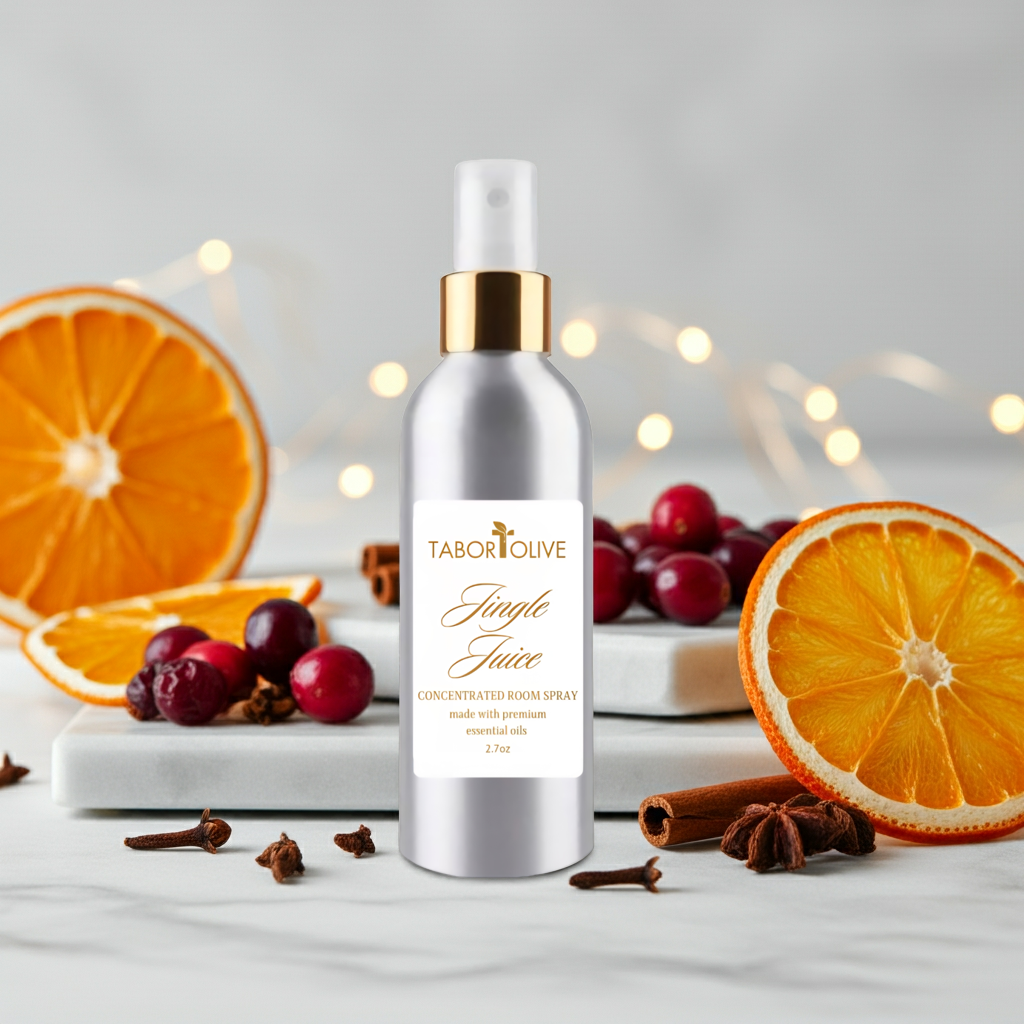 Bottle of Tabor Olive room spray surrounded by oranges, cranberries, and cinnamon sticks on a light background