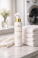 Load image into Gallery viewer, Tabor Olive Fresh Linen natural odor Neutralizing spray bottle on a marble countertop with folded white towels and a washing machine in the background.
